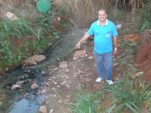 O vereador José Renato próximo a água empossada no canal de escoamento de água do Bairro Guaíra E:mau cheiro e o surgimento de insetos